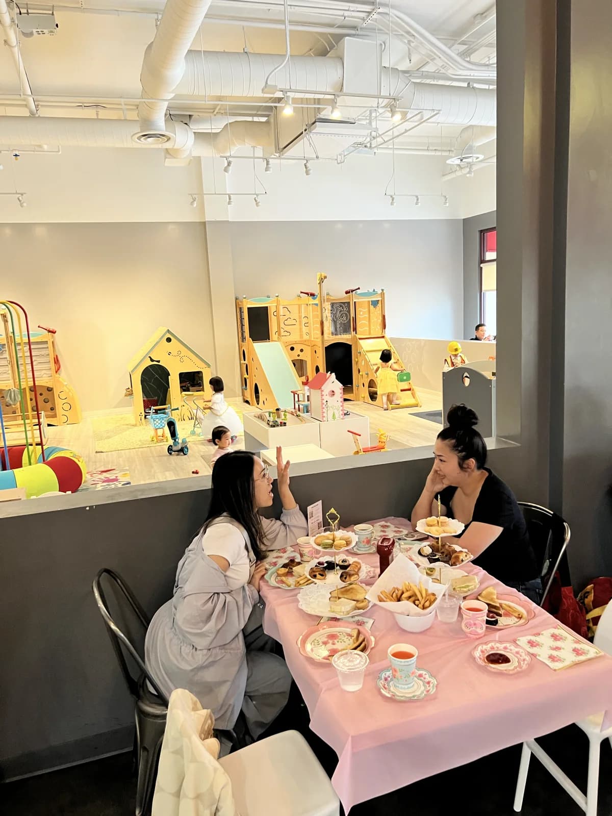 Parents dining beside the indoor play area at My Little Paris