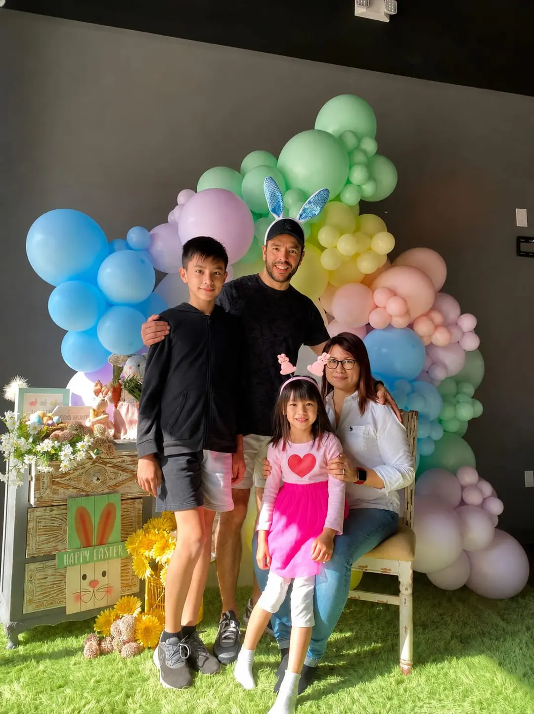 A family posing together in front of pastel balloons and Easter decorations
